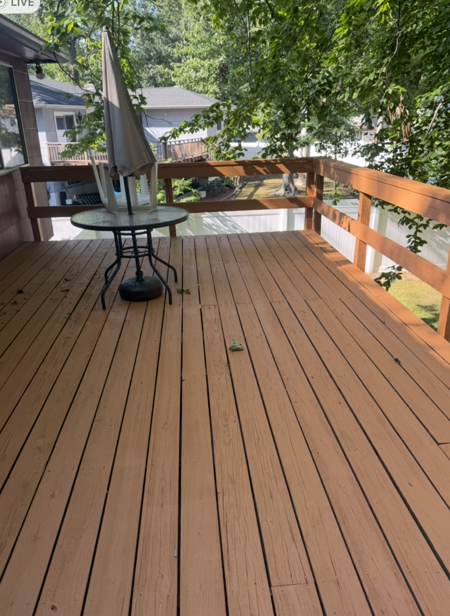 Completed deck remodel — refreshed warm-toned deck boards and stained railing beside sunroom